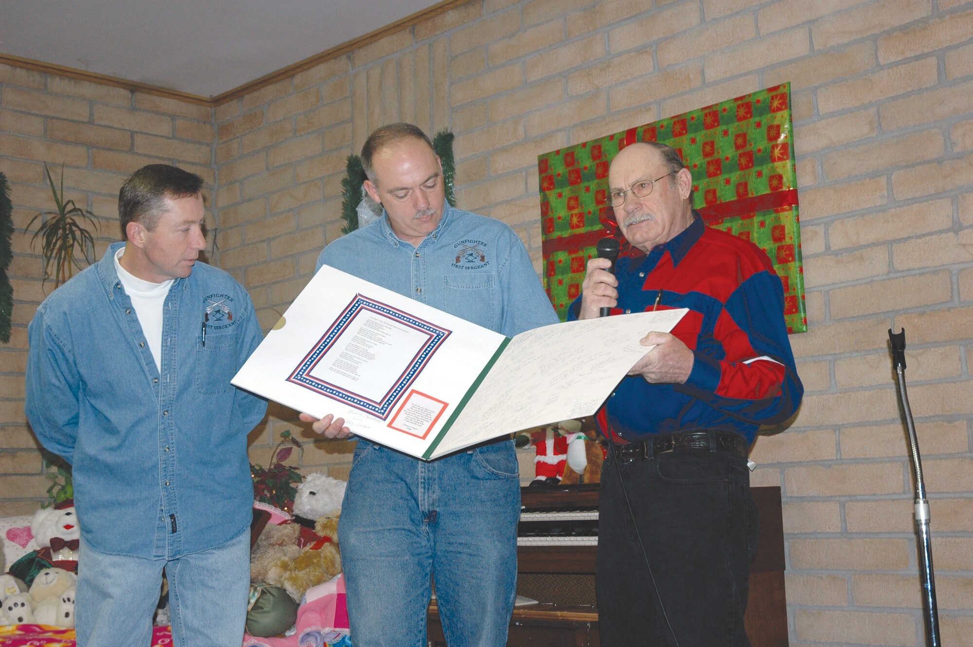 Master Sgts. Ed Van Etten, First Sergeant Association president, and Jeff Waters, FSA vice president, receive a Christmas card from Ed Eagans on behalf of SilverCrest II during a ceremony Saturday. (U.S. AIr Force Photo/Staff Sgt. Jasmine Reif)
