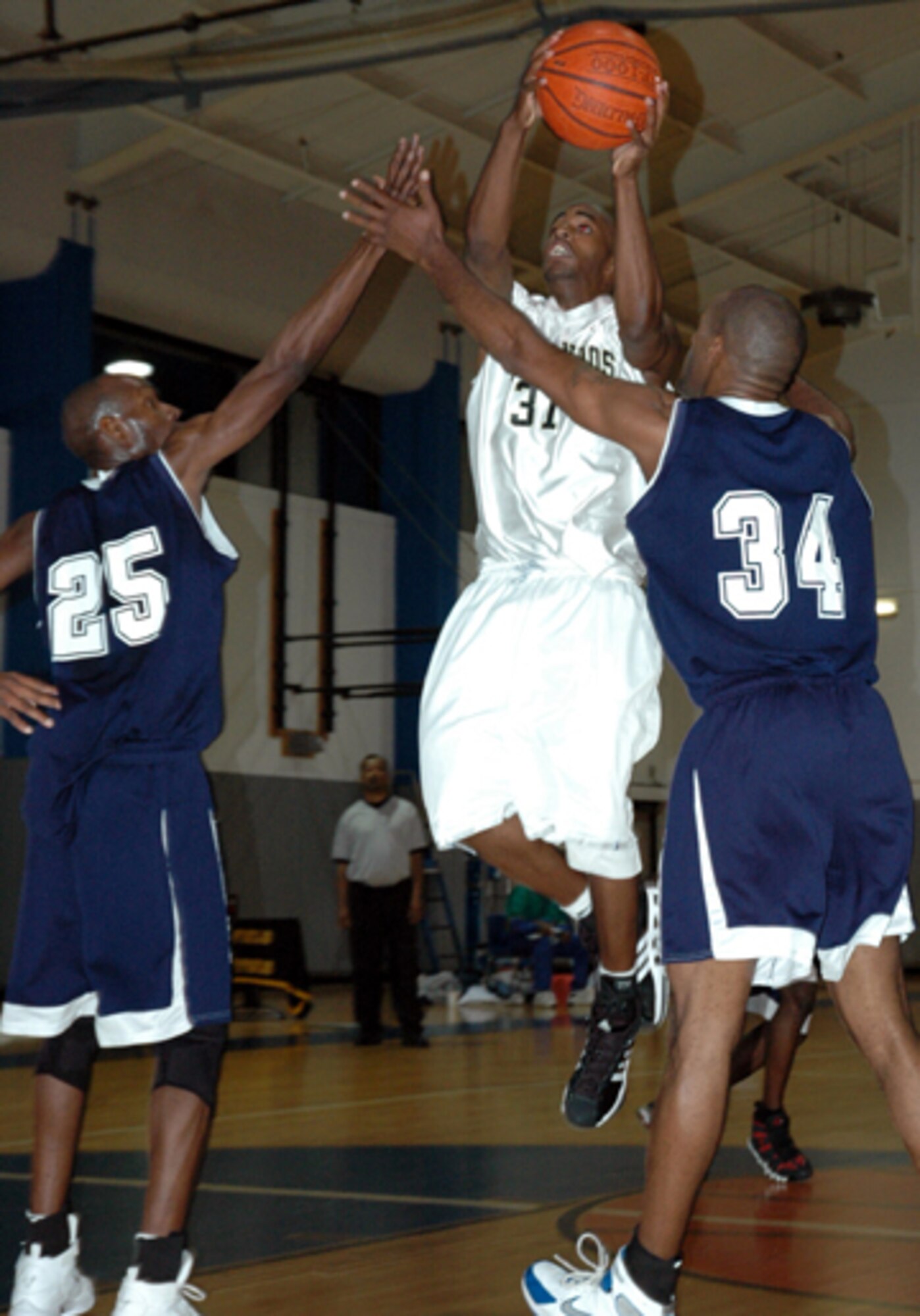 Hurlburt Commandos guard Davon Martin soars over two Naval Station Mayport varsity basketball players during the game Dec. 9. Hurlburt won both of the weekend games 87-75 and 83-78. (U.S. Air Force Photograph by MSgt Stuart Camp)