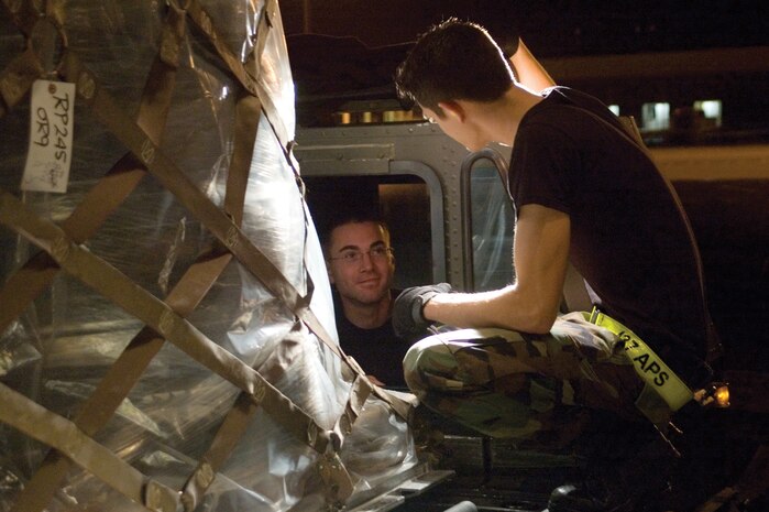 Airman 1st Class Russell Berry (left) and Airman 1st Class Johnathan Lemond, 437th Aerial Port Squadron air transportation specialists, discuss aircraft loading procedures while loading a Boeing 747 on the flightline in the early morning hours Dec. 13. (U.S. Air Force photo/Airman 1st Class Sam Hymas)