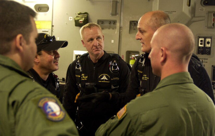 Andy Serrano (left), Andy Burch (center) and Chip Bowlin (right) discuss their upcoming jump, with loadmasters, Tech. Sgt. Daryl Hillman and Staff Sgt. Samuel Stewart, both members of the 437th Operations Support Squadron combat tactics, prior to their jump from a C-17 Globemaster III over the Miami Dolphins football game Oct. 10. Mr. Serrano, Mr. Burch and Mr. Bowlin are retired Soldiers who volunteer as members of the U.S. Special Operations Command Parachute Demonstration Team from MacDill Air Force Base, Fla. (U.S. Air Force photo/Tech. Sgt. Paul Kilgallon)