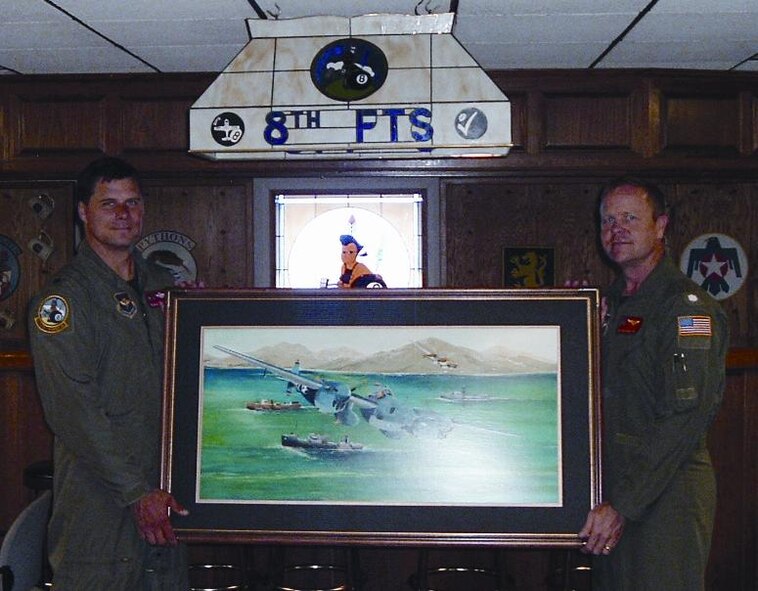 (Photo by Jim Malachowski) Navy Cmdr. Brian Osborn, 8th Flying Training Squad-ron commander, and Lt. Col. Steve Fournier,  8th FTS director of operations, unveil an oil painting depicting a P-38 and F-5 flying over enemy ships near Simpson Harbor, Ra-baul. The painting, by aviation artist Paul Wentzel, was nominated to hang in the U.S. Air Force Art Collec-tion.
