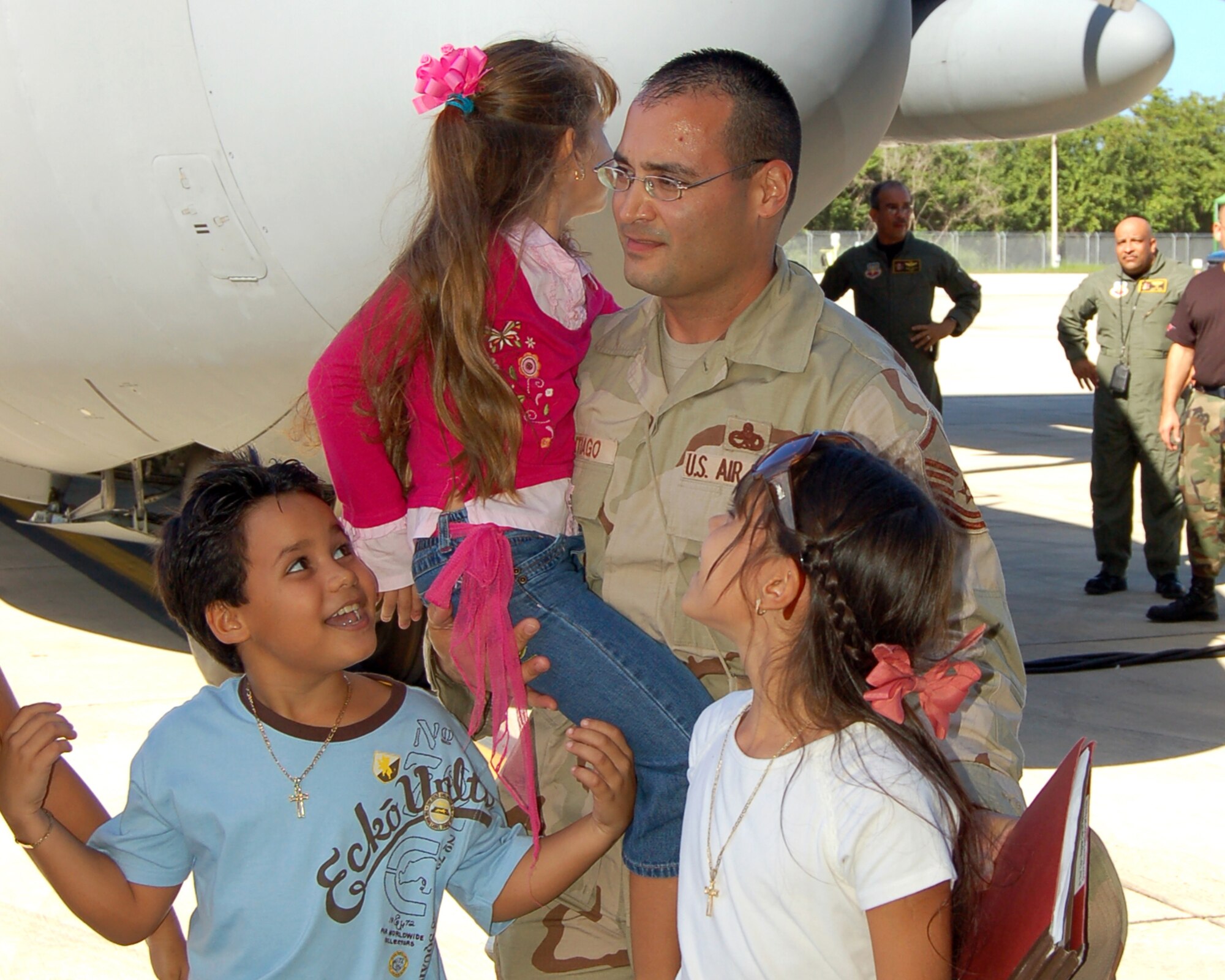 Master Sgt. Ramon Santiago holds his daughter, Camila, as two of his other children, Ramon and Arianna, welcome him home at Muñiz Air National Guard Base, Puerto Rico, Dec. 16. The 156th Aircraft Maintenance Squadron jet engine mechanic was deployed to Bagram Air Base, Afghanistan. The unit is part of the 156th Airlift Wing of the Puerto Rico Air National Guard. (U.S. Air Force photo/Louis A. Arana-Barradas)