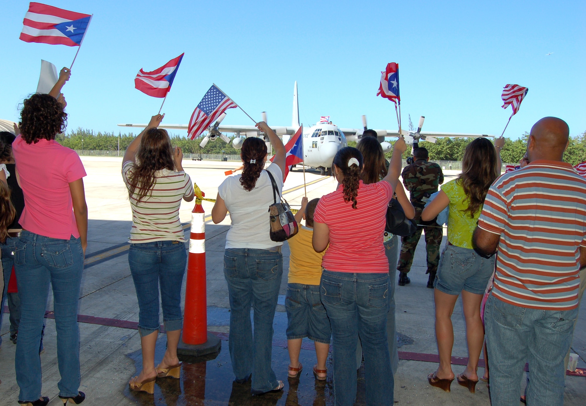 With American and Puerto Rican flags flying, more than 150 people welcomed home 26 members of the 198th Airlift Squadron on their return home to Muñiz Air National Guard Base, Puerto Rico, Dec. 16. The unit deployed to Bagram Air Base, Afghanistan. The squadron is part of the 156th Airlift Wing of the Puerto Rico Air National Guard. (U.S. Air Force photo/Louis A. Arana-Barradas)