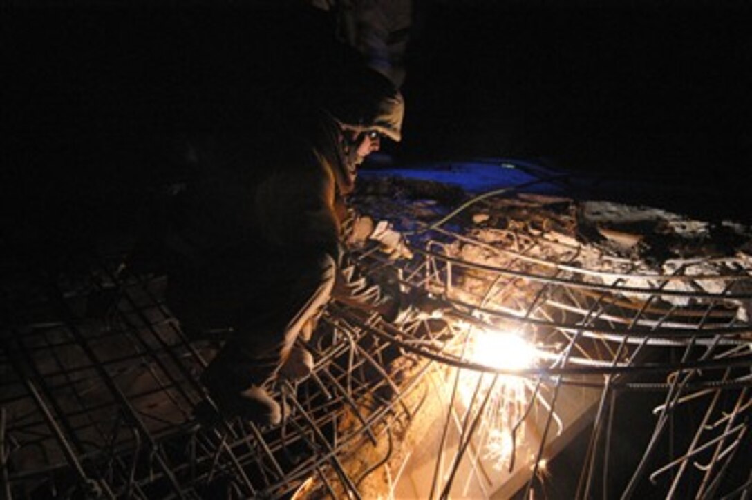 U.S. Navy Petty Officer 3rd Class Bill Adams, with Naval Mobile Construction Battalion 18, cuts away bent rebar from a damaged bridge near Al Khalidiyah, Iraq, Dec. 10, 2006. 