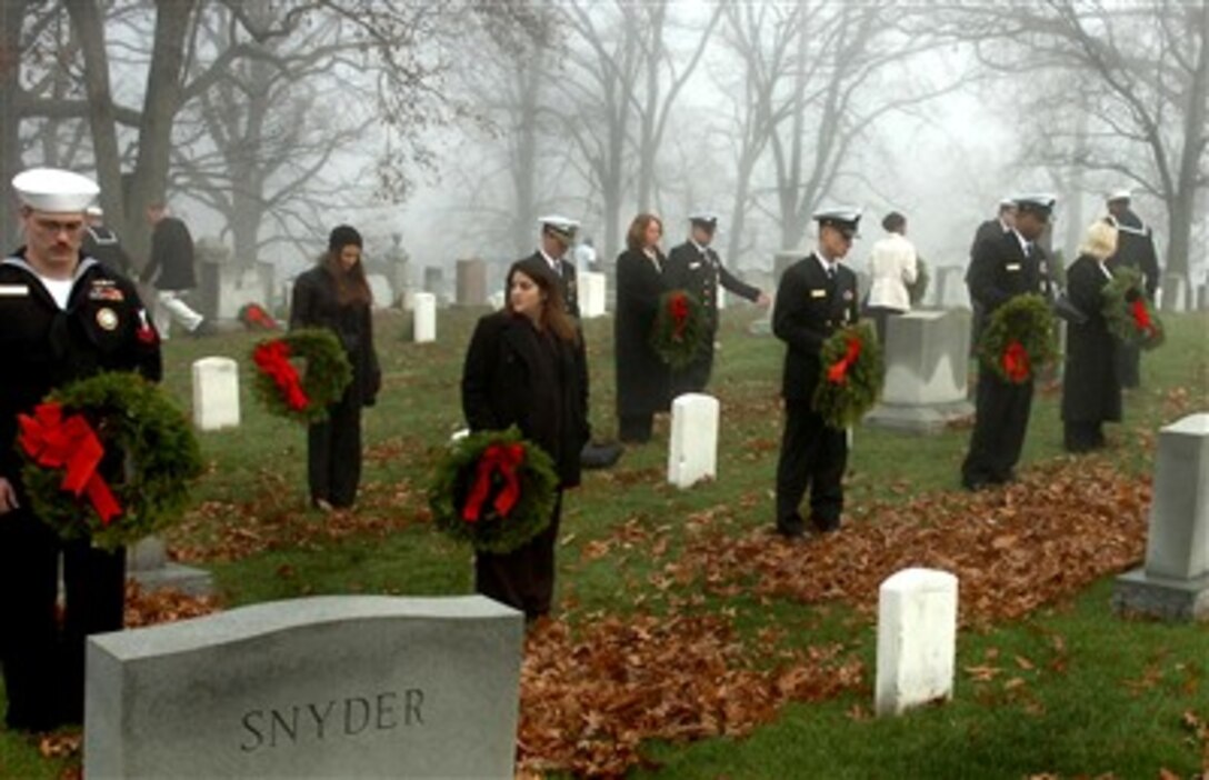 U.S. Navy Sailors and family members prepare to lay wreaths on tombstones at Arlington National Cemetery in Arlington, Va., on Dec. 14, 2006, as part of Wreaths Across America. The annual event honors veterans by placing memorial wreaths at state and national cemeteries and veteran's monuments across the country. 