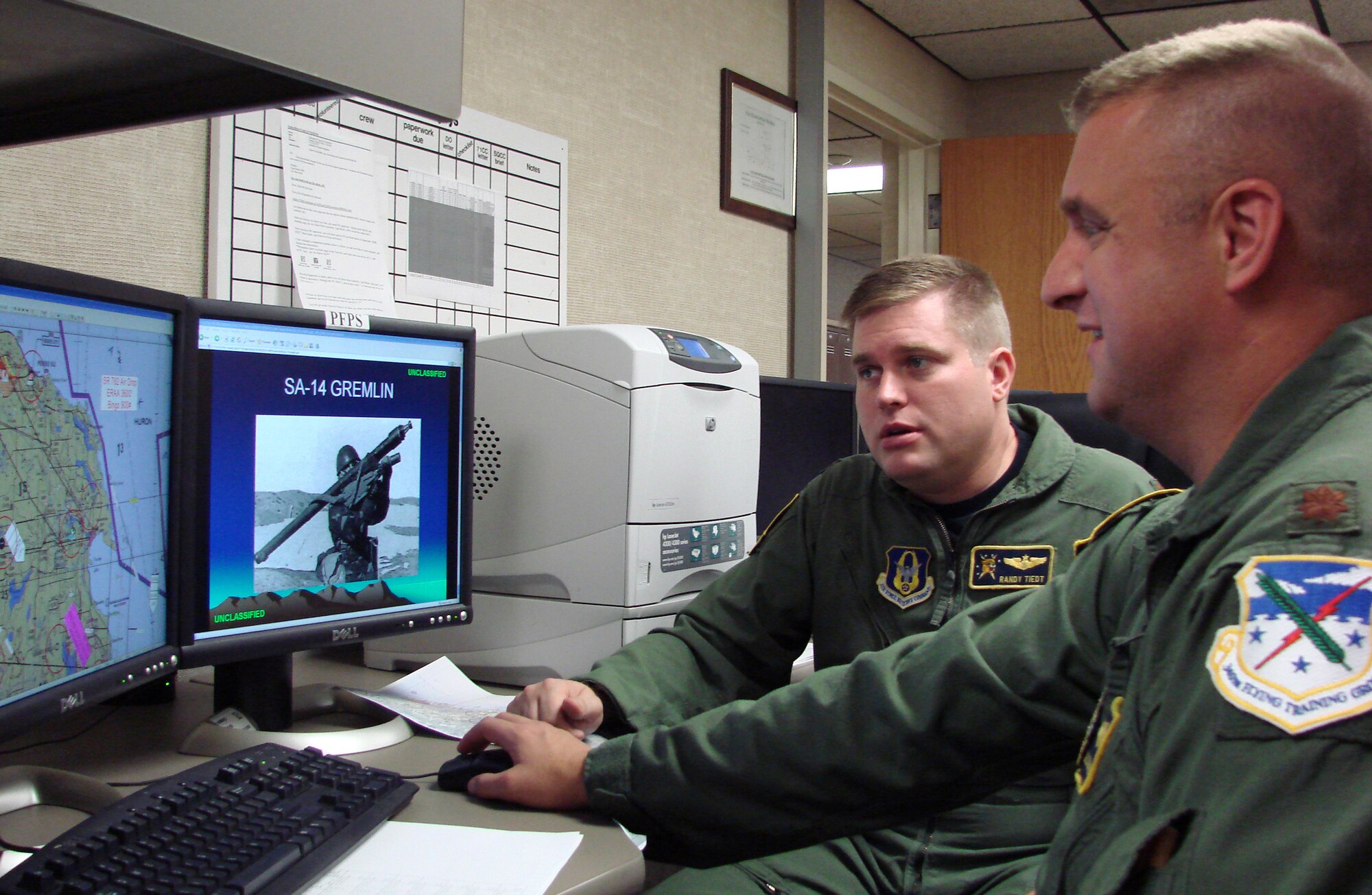 Majors Randy Tiedt and Doug Stouffer update a simulated threat on the Portable Flight Planning Software they customized to incorporate simulated threats into the mission planning of T-1 students pilots Dec. 15 at Vance Air Force Base, Okla. The new process provides the students with an early exposure to the reality of combat. The two T-1 Jayhawks pilots are assigned to the 5th Flying Training Squadron. (U.S. Air Force photo)                   