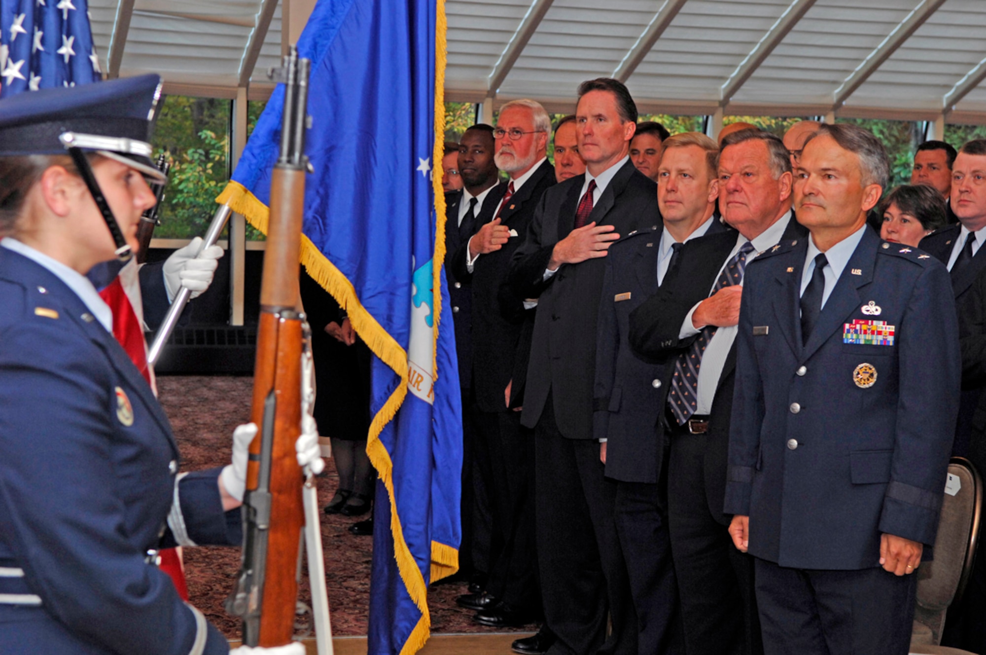 Hanscom leaders and Honorary Commanders pay their respects while the Air Force Band of Liberty plays the national anthem during the Honorary Commander induction ceremony Tuesday. Six of the seven Honorary Commanders were passed the 60th Anniversary Flag of the Air Force signifying their acceptance of their new position here. The seventh Honorary Commander, Peter Zimmerman was unable to attend the Tuesday event and will be inducted at a later time. The Honorary Commanders program is designed to increase public awareness and understanding of the armed forces and the missions, policies, programs and people of the Electronic Systems Center. (US Air Force Photo by Mark Wyatt)