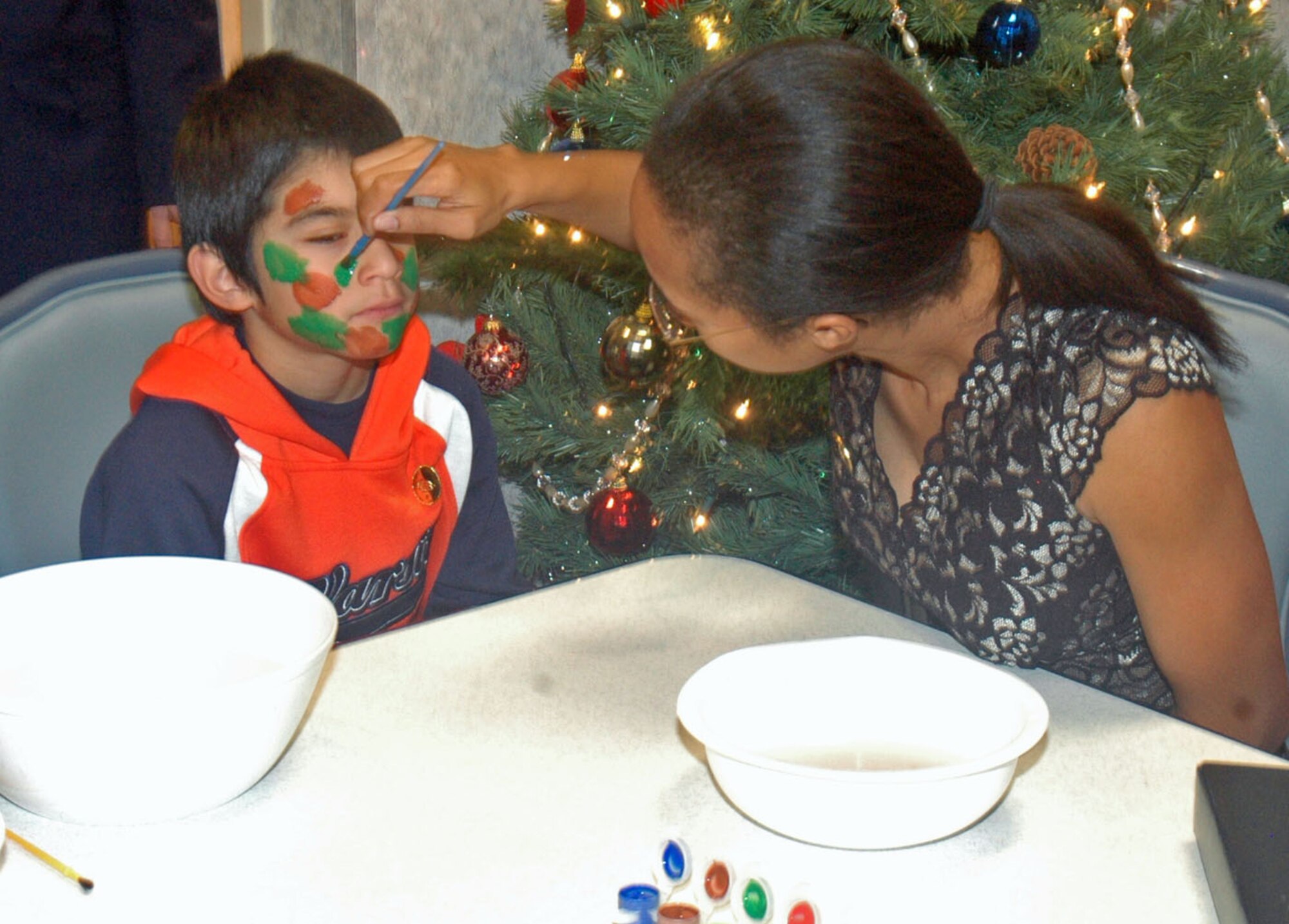 After watching a magician, a local boy gets his face painted in camouflage colors by a volunteer.