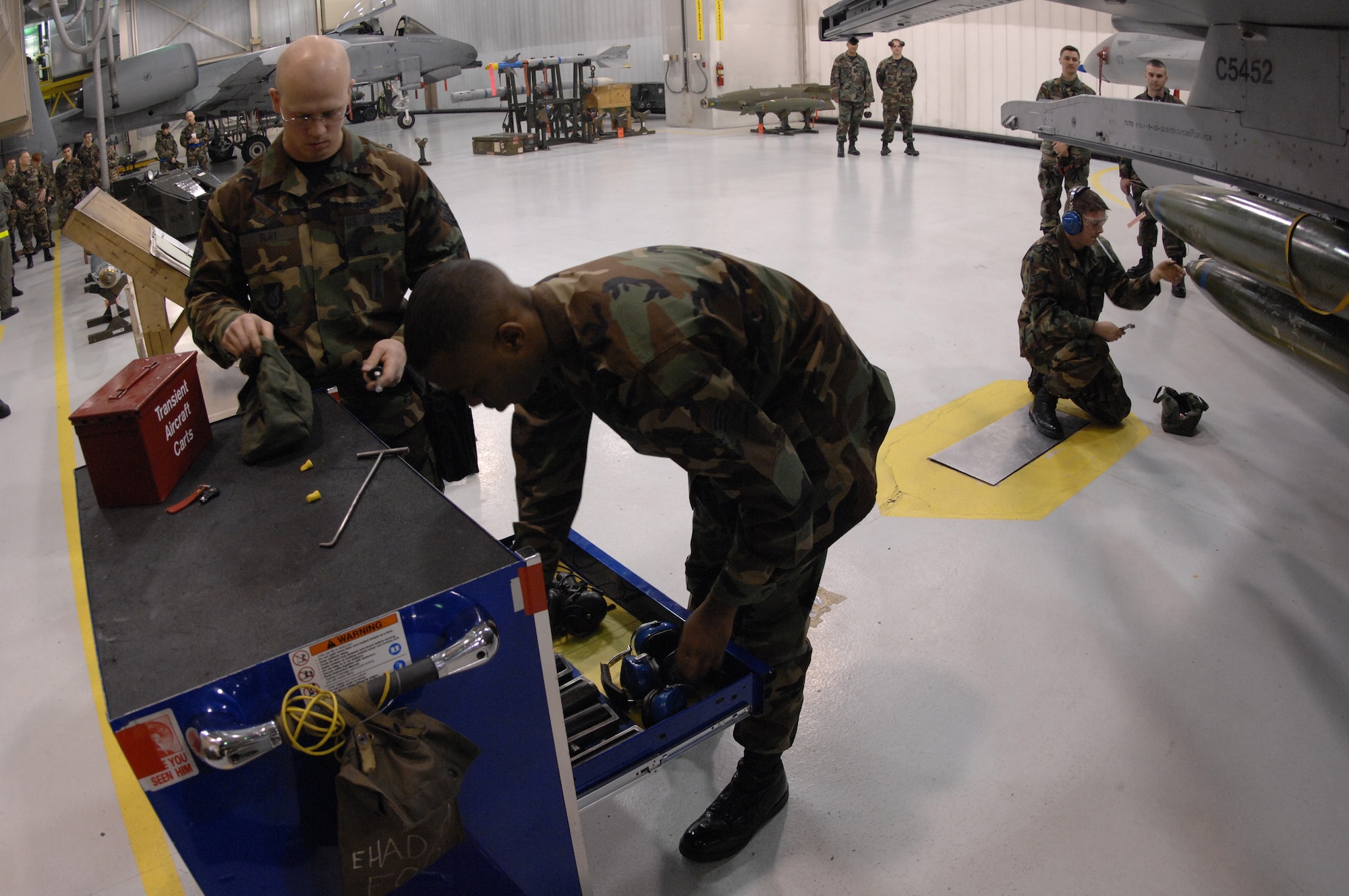 EIELSON AIR FORCE BASE, Alaska -- Staff Sgt Aaron Slay (left at work bench) and Senior Airman Corneilius Cutler (right at work bench) put tools away while Senior Airman Michael Lee (at aircraft) works on a MK-82 bomb during the Load Crew of the Quarter contest here on 15 December. The Airmen represent the 18th Aircraft Maintenance Unit (AMU) and the quarterly contest pitts the 18th AMU versus the 355th AMU. Both teams loaded 2 MK-82 low drag bombs and one AIM-9 sidewinder missile to their respective aircraft.
(U.S. Air Force Photo by Staff Sgt Joshua Strang)