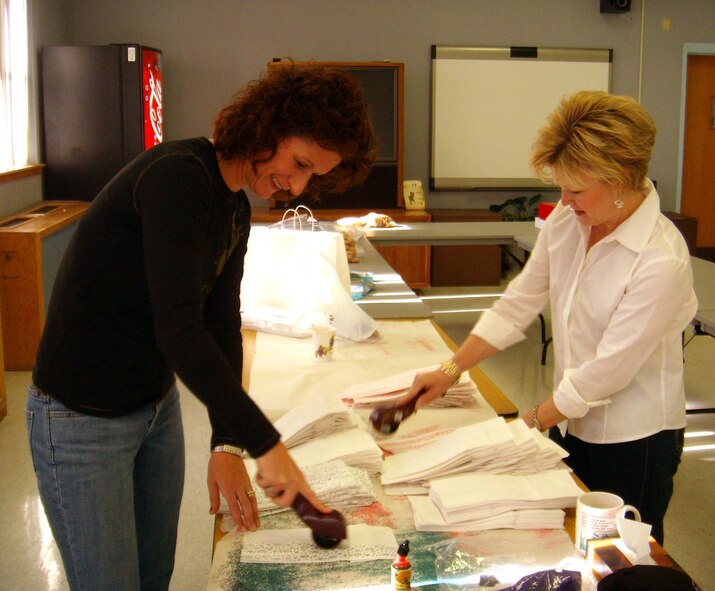 Mrs. Karen Cooke and Mrs. Dawn Goldfein, Holloman Officers' Spouses Club members, decorate paper bags for the Airmen's Cookie Drive Dec. 14. The cooke bags were delivered to Airmen in the dorms Dec. 15. (U.S. Air Force photo by Airman 1st Class Heather Stanton)