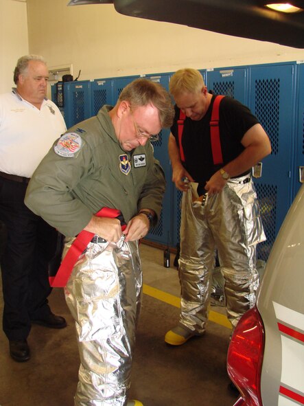 (Photo by Capt. Tony Wickman) Fire Chief Norman Yeingst watches Col. Bryan Benson, 71st Flying Training Wing commander, and Col. Christopher Thelen, 71st Mission Support Group commander, don bunkers to conduct fire training with the Vance Fire Department Tuesday. The colonels were honorary firefighters for the day and experienced dousing an 1,800-degree aircraft fire at the airfield rescue firefighting training facility. See the Sept. 1 Airscoop for more photos and information about firefighter training.