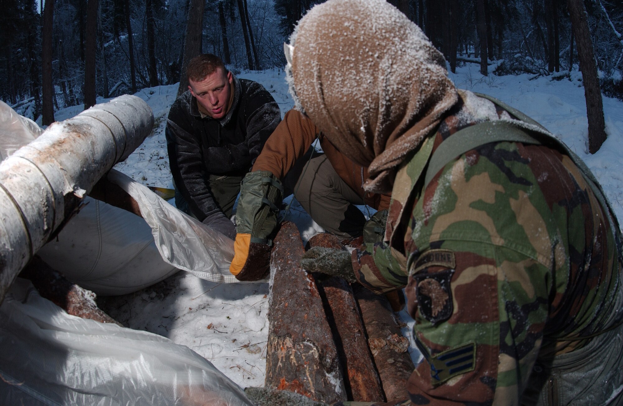 EIELSON AIR FORCE BASE, Alaska -- Senior Airman Jason Naquin (front) and Senior Airman Ryan Perry (back) of Fort Campbell, Kentucky, 19th Air Support Operations Squadron and Staff Sgt. Mathew Scharder of Kulis Air National Guard Base, Alaska, 212th Pararescue Squadron (middle) work together on placing the kick logs into place to finish their shelters on 14 December, 2006. The kick log is designed to be an easy exit if their shelters gets buried in the snow. They are participating in the Arctic Survival School only available at Eielson AFB. This five day course teaches the basic survival skills needed to know such as making fire, shelter, catching food and using flares to signal for help.
(US Air Force Photo by Airman Jonathan Snyder)