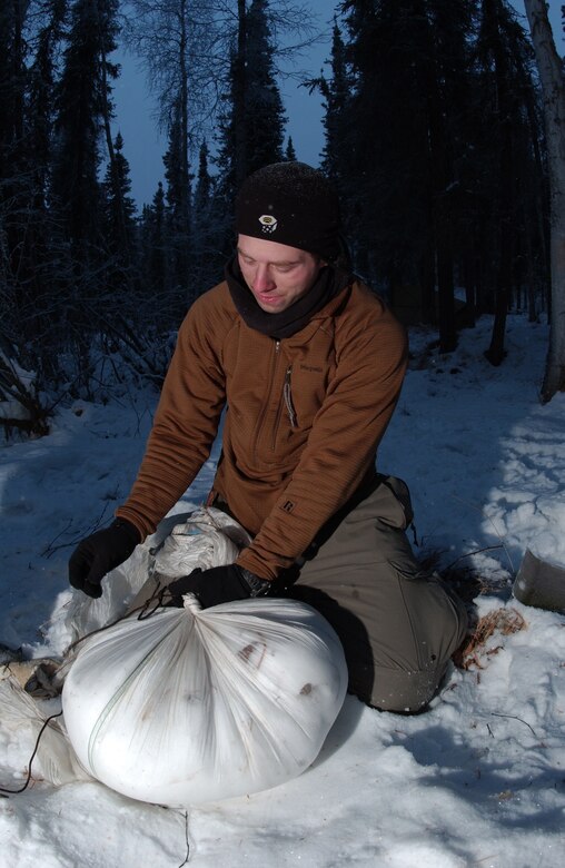 EIELSON AIR FORCE BASE, Alaska -- Staff Sgt. Mathew Scharder of Kulis Air National Guard Base, Alaska, 212th Pararescue Squadron, ties a canopy together full of snow which will be used for the door of his shelter on Dec. 14. He is participating in the Arctic Survival School only available at Eielson. This five-day course teaches the basic survival skills needed to know such as making fire, shelter, catching food and using flares to signal for help.  
(U. S. Air Force Photo by Airman Jonathan Snyder).