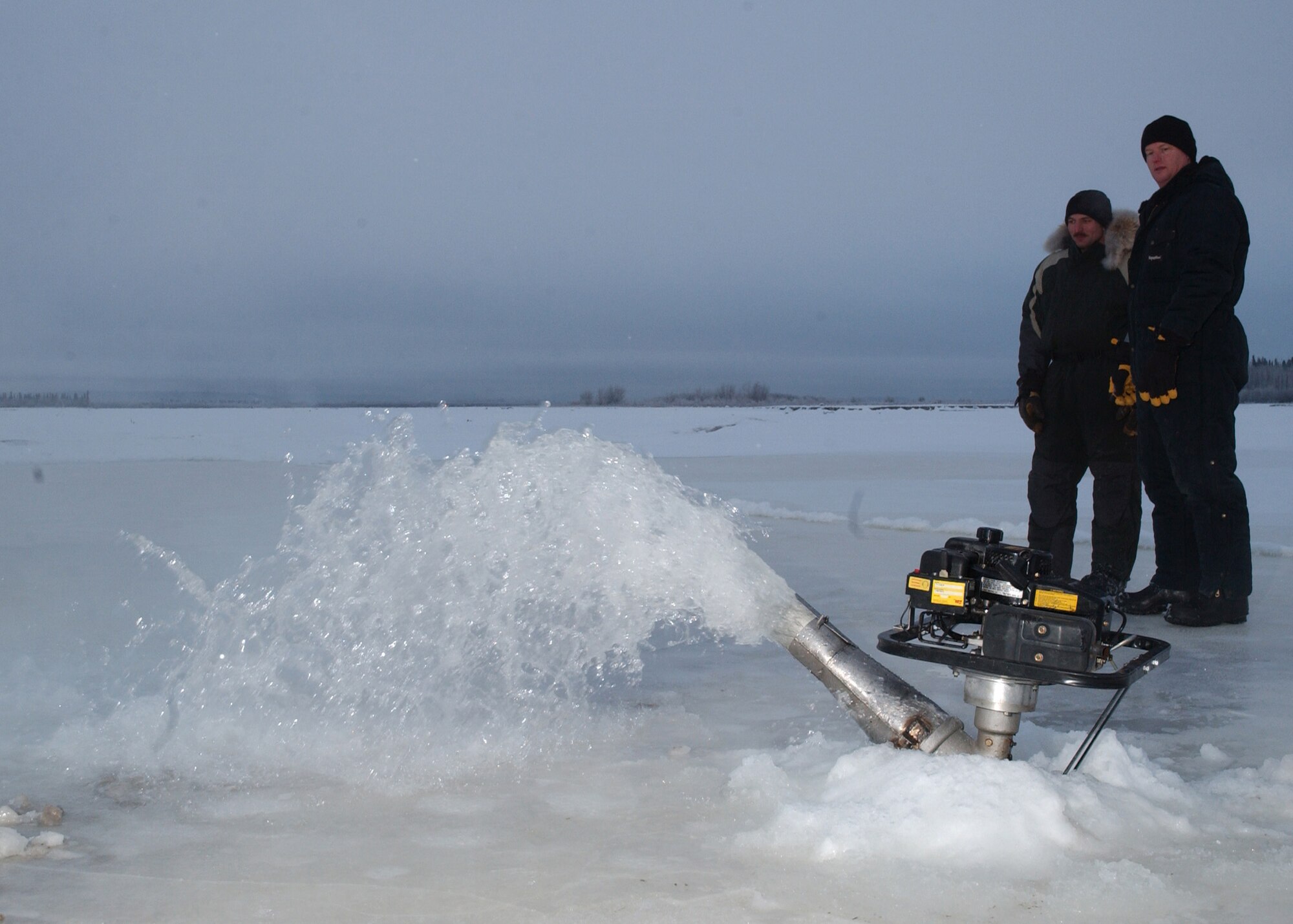 EIELSON AIR FORCE BASE, Alaska -- Master Sgt. Andy Harper and Tech. Sgt. Scott Fletcher, both from the 354th Civil Engineer Squadron, keep an eye on water being pumped from the river to build up the ice bridge. The ice bridge takes about five weeks to complete in sub-zero weather. It is five-foot deep, a mile long and capable of supporting more than 110 tons -- which completely vanishes a few months later. The ice bridge helps 354th CES members access and perform annual maintenance on Eielson's training and bombing ranges. (U.S. Air Force photo by Airman Jonathan Snyder).