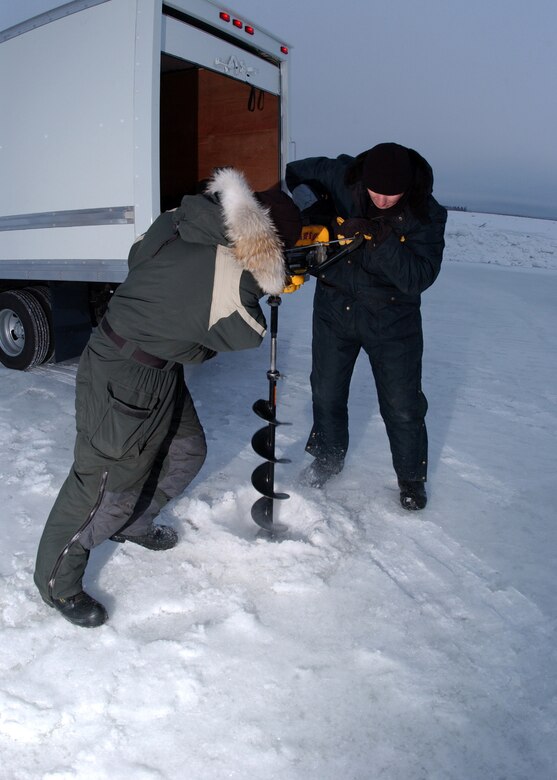 EIELSON AIR FORCE BASE, Alaska -- Master Sgt. Andy Harper and Tech. Sgt. Scott Fletcher, both from the 354th Civil Engineer Squadron, use an auger to measure the ice thickness. If the ice is not thick enough, water pumps will be placed in the drilled hole to help build the ice bridge. The ice bridge takes about five weeks to complete in sub-zero weather. It is five-foot deep, a mile long and capable of supporting more than 110 tons -- which completely vanishes a few months later. The ice bridge helps 354th CES members access and perform annual maintenance on Eielson?s training and bombing ranges. (U.S. Air Force photo by Airman Jonathan Snyder).