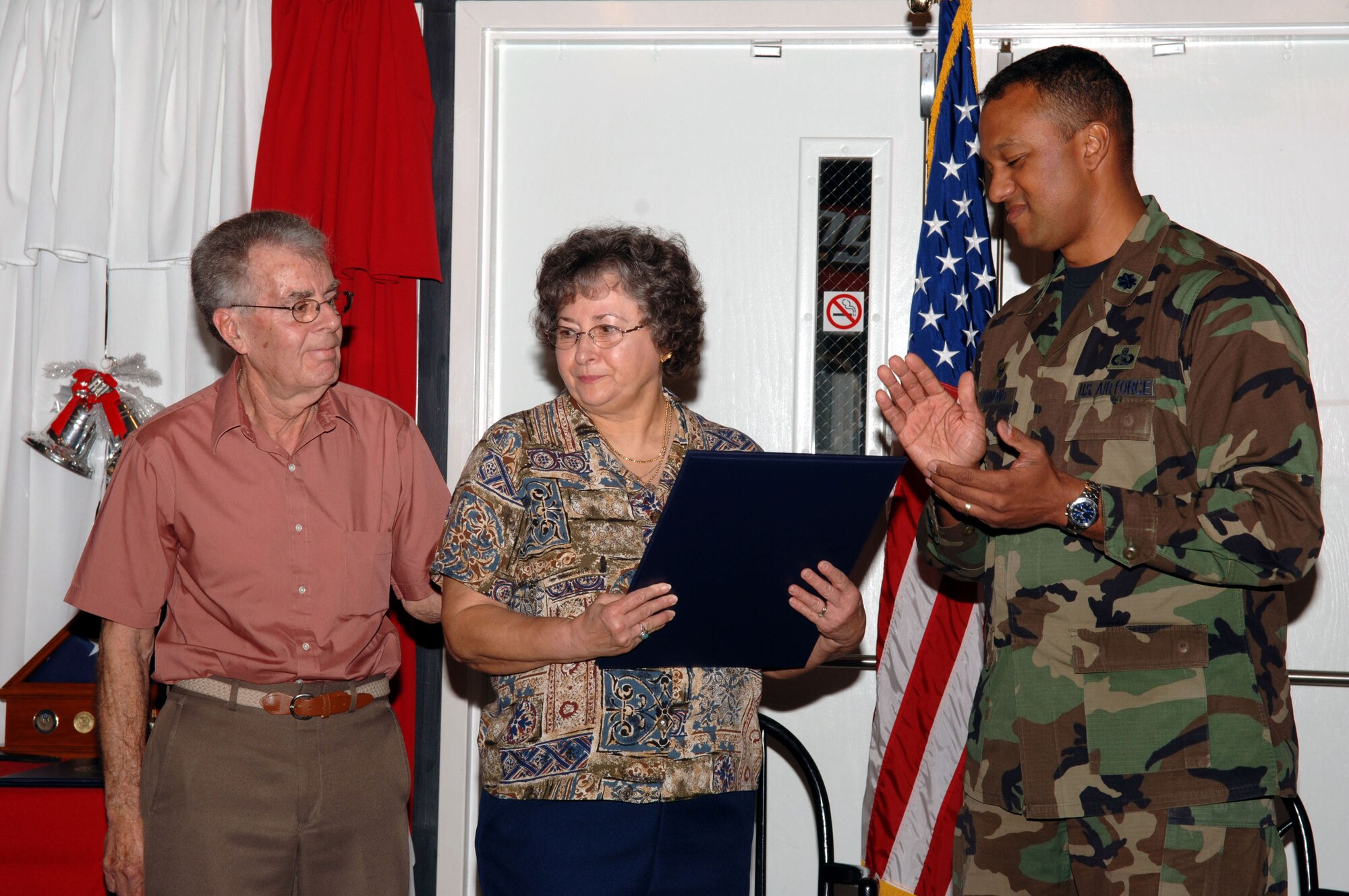 Bob Duguid (left), his wife, Diane and Lt. Col. Michael Hammond, 1st Special Operations Communication Squadron, honor Mr. Duiguid at his retirement ceremony Dec. 15. Mr. Duguid is retiring after 48 years of working in the visual information field - of which 22 of those years were spent at Hurlburt Field. (U.S. Air Force Photograph by Senior Amn Andy Kin)