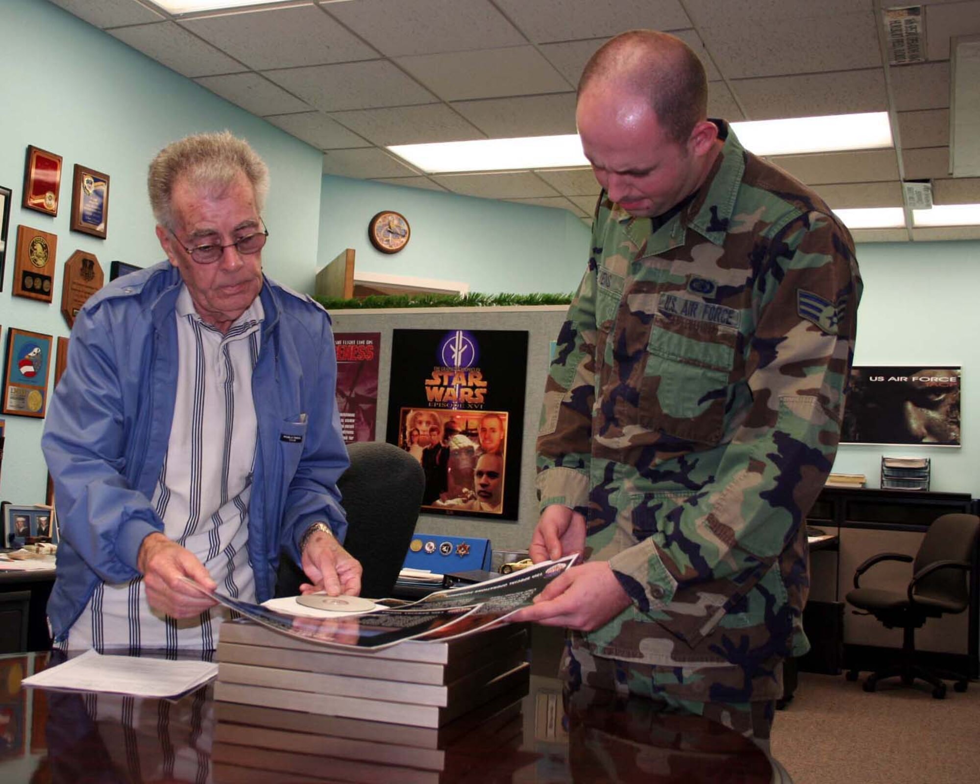 Bob Duguid (left) and Senior Airman Gary Stevens, 1st Special Operations Communications Squadron, proof the graphics in a publication they've produced. Mr. Duguid is retiring after 48 years of service - 22 of those years at Hurlburt Field. (U.S. Air Force Photograph by Jamie Haig)