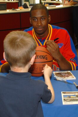 Robert Turner, a Harlem Globetrotter, signs a basketball for Larsen Gray, 6, son of Staff Sgt. Michael Gray, 314th Communications Squadron, during a meet and greet at the fitness center Dec. 14. The Globetrotter visited the base to show support for the troops during the holiday season.