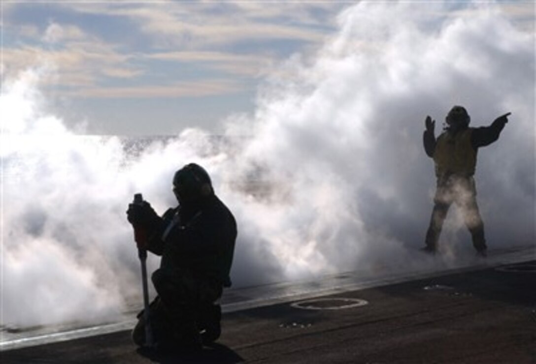 Aboard the Nimitz-class aircraft carrier USS Theodore Roosevelt, an aviation boatswain's mate guides an F/A-18 Super Hornet to the catch while conducting flight operations, Dec. 9, 2006.