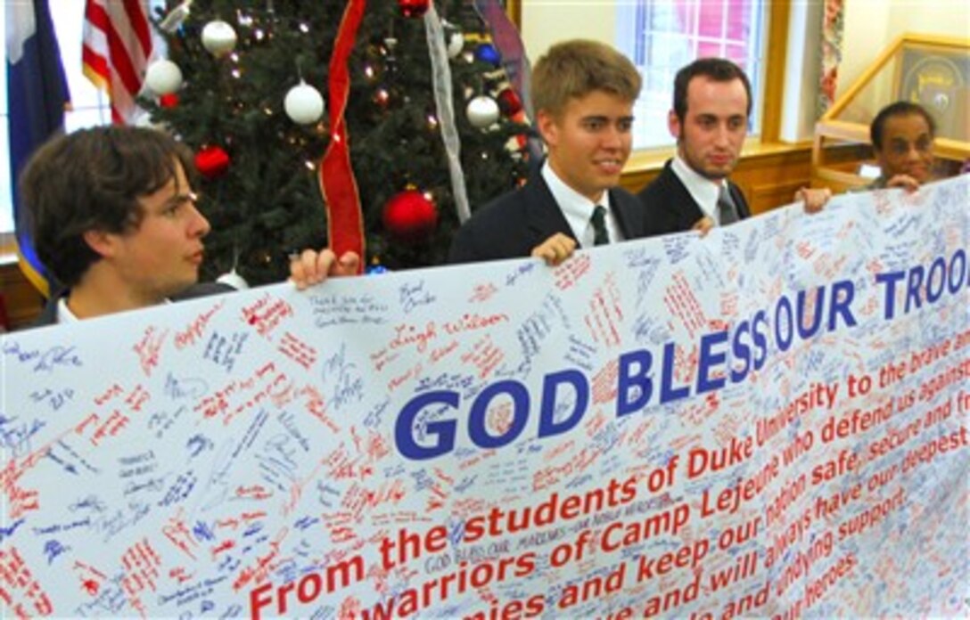 Steven Miller, Jamie Deal, and David Bitner, members of the Duke Conservative Union, and Col. Adele E. Hodges, commanding officer of Marine Corps Base Camp Lejeune, N.C., and hold a poster, signed by hundreds of Duke students, Dec. 13.




