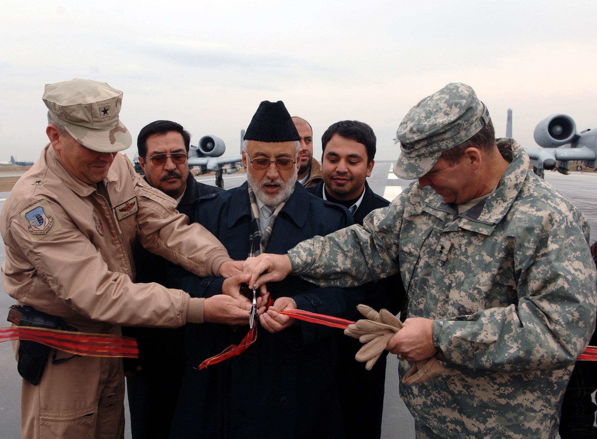 Brig. Gen. Christopher Miller, 455th Air Expeditionary Wing commander (L) along with Abdul Taqwa, governor of Parwan Province and Maj. Gen. Benjamin Freakley cut the ribbon officially opening the new runway at Bagram Airfield Dec. 20.  The new runway is 2000 feet longer than the previous runway and was designed to accept the majority of aircraft in the military inventory, although it can accept larger aircraft such as the C-5 Galaxy and Boeing 747 if necessary. (U.S. Air Force photo/Tech. Sgt. Joseph Kapinos)