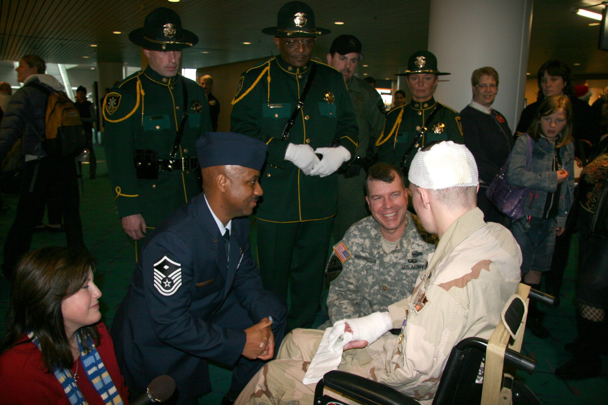 Master Sgt. John Conway, left, 939th Civil Engineer Squadron first sergeant and Maj. Michael Warrington, 141st Brigade Support Battalion commander Oregon Army National Guard talk with Army Sergeant John P. King about hospital food and getting a prime rib dinner after he was escorted by members of the 939th Air Refueling Wing's honor guard through a line of Multnomah County Sheriff, Port of Portland police, and Portland Police Bureau honor guards who played the bagpipes and rendered salutes to welcome the young soldier home to Portland, Ore. Dec. 20, 2006.  Sergeant King, who was wounded in Iraq in Aug. was given a 7-day pass from Brooks Army Hospital, San Antonio, Texas to visit his family during the holidays and will celebrate his 26th birthday on Friday before returning to the hospital from more treatment. (U.S. Air Force Photo/Ruby Zarzyczny)