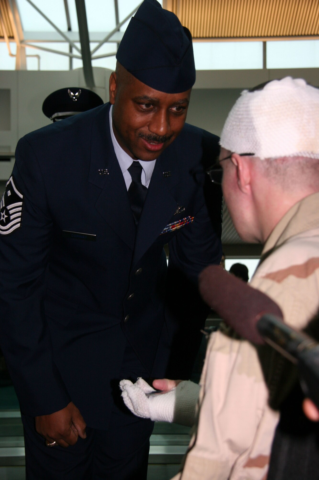 Master Sgt. John Conway, 939th Civil Engineer Squadron first sergeant presents a 939th Air Refueling Wing coin to Army Sgt. John P. King when he arrived at the Portland International Airport Dec. 20, 2006.  Sergeant King was wounded in Iraq when his Bradley tank ran over a road side bomb.  His mother contacted Multnomah County Sheriff Sergeant and long time friend Kathy Gorton who coordinated a special homecoming for the 25 year-old sergeant.  Master Sgt John Conway, Air Force Reservist, is also a Multnomah County deputy and was honored to welcome the young soldier home.  (U.S. Air Force Photo/Ruby Zarzyczny)