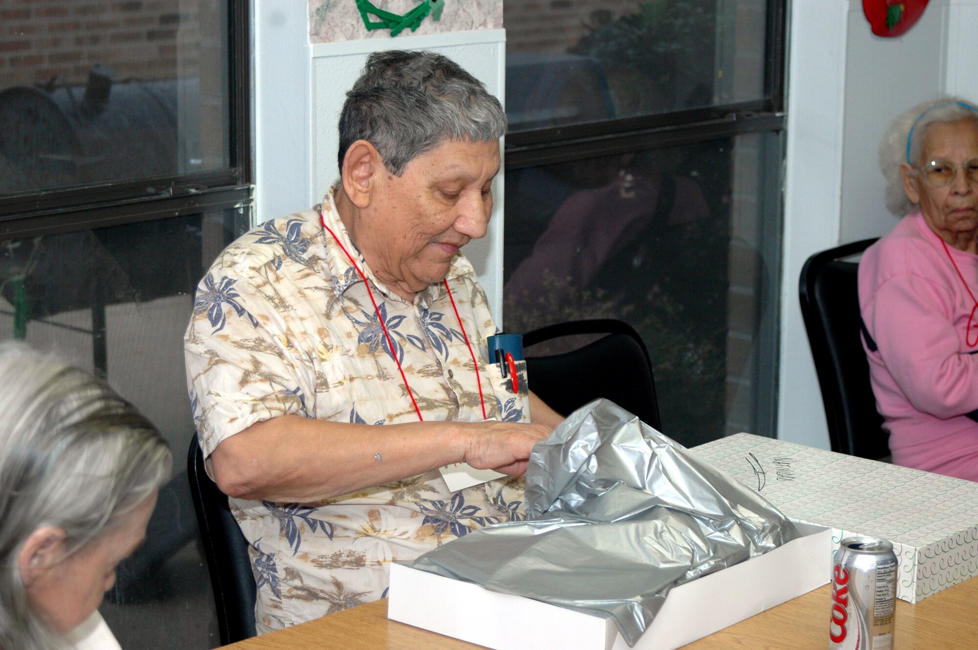 Natividad Huerta, a resident of the Grayson Square Health Care Center in San Antonio opens a Christmas present given by members of the 737th Training Group and the Air Force Personnel Center on Dec. 20 at the Grayson Square Health Center. Group and AFPC personnel adopt the residents, who range in age from 21 to 103, and bring wrapped gifts to help brighten the residents' holidays. (USAF photo by Staff Sgt. Tim Russer)