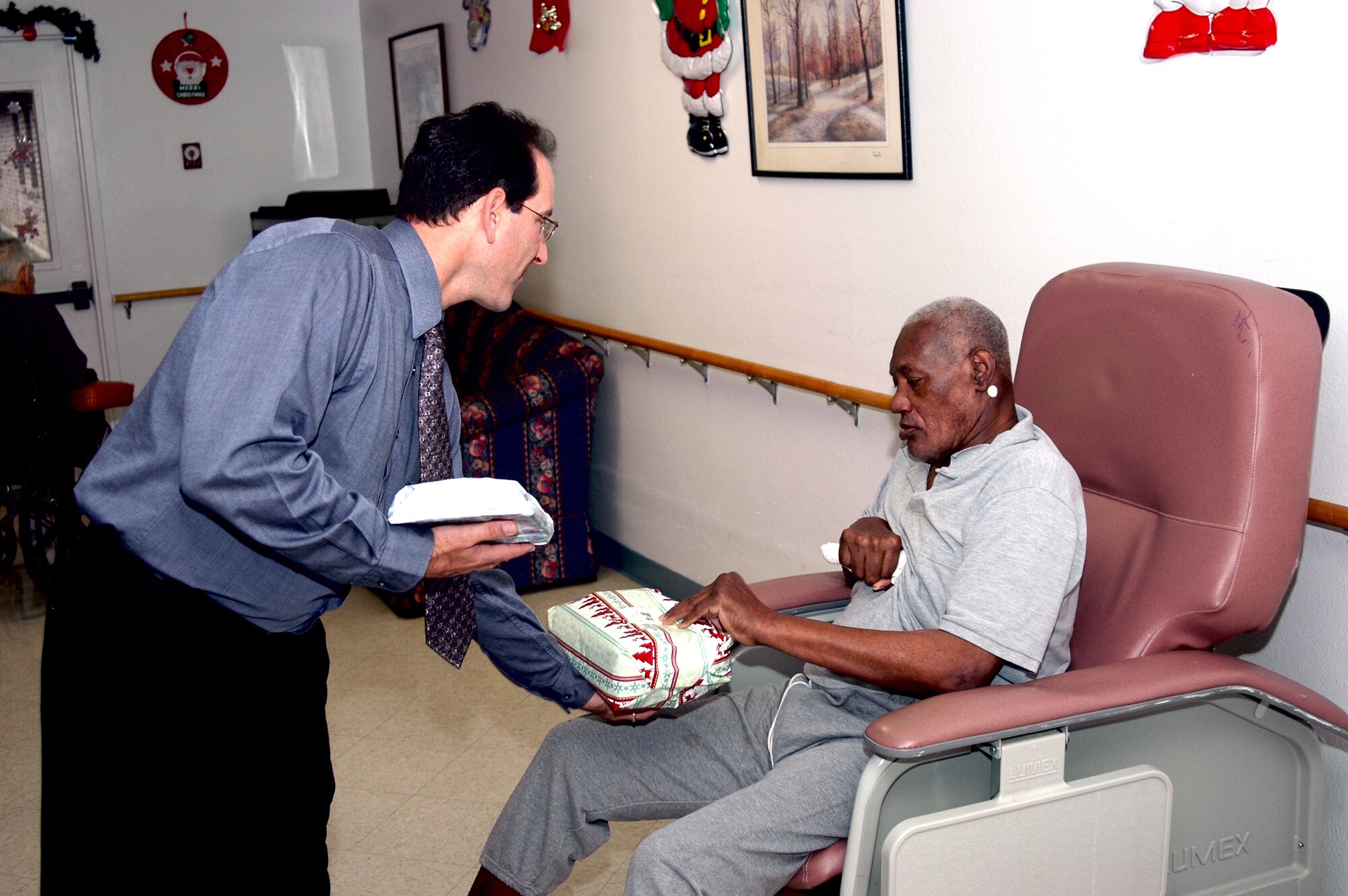 D. Jim Steele, chief of Basic Military Training Scheduling, 737th Training Support Squadron at Lackland Air Force Base, Texas, gives Willie Wright, a resident at the Grayson Square Health Care Center in San Antonio, a Christmas gift Dec. 20 at the Health Care Center during a holiday gift presentation sponsored by the 737th Training Group and Air Force Personnel Center. Mr. Steele has played a key role in organizing this event since 1998. (USAF photo by Staff Sgt. Tim Russer)    