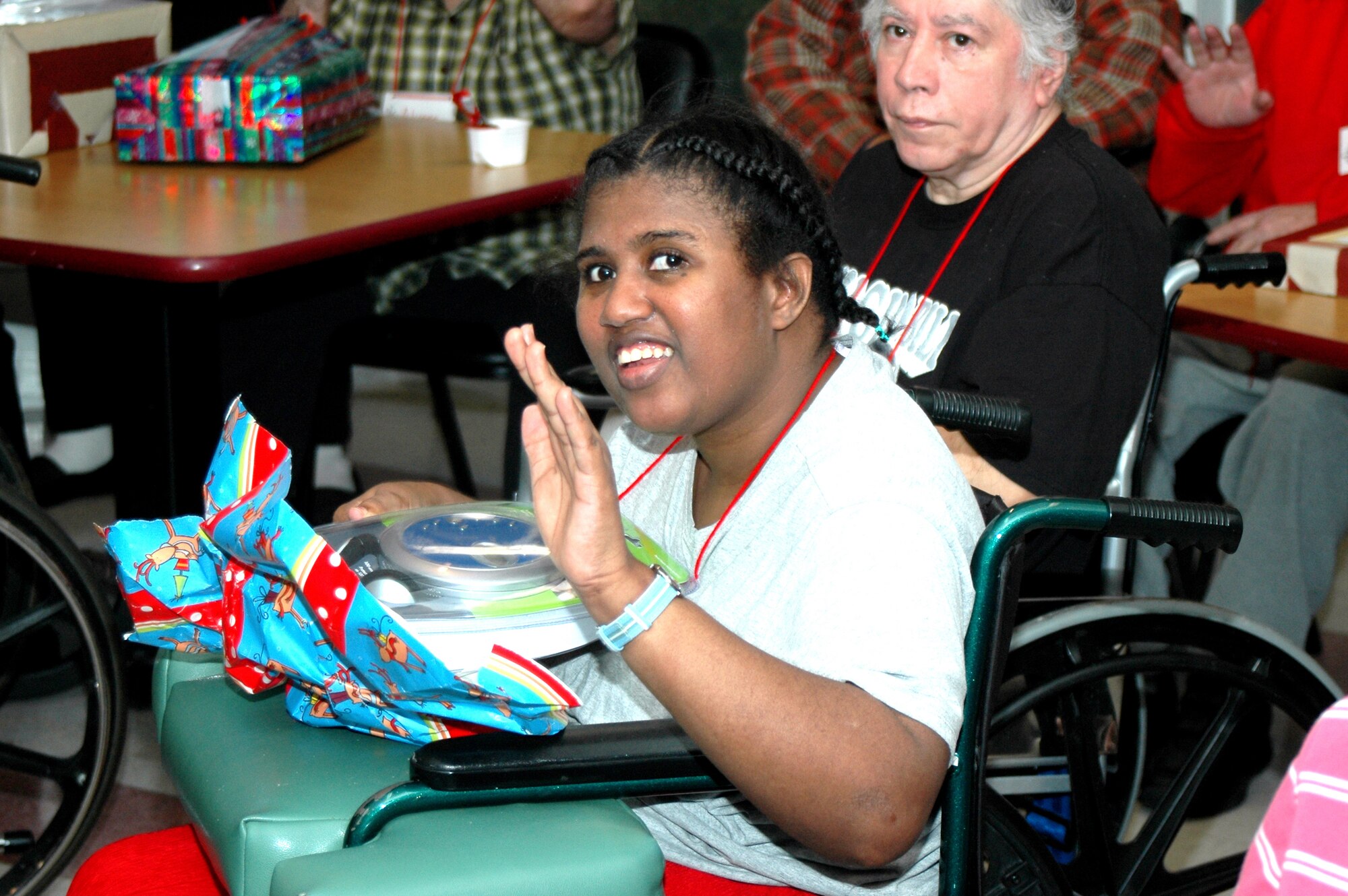 Waynetta Deolach, one of the 46 residents of the Grayson Square Health Care Center in San Antonio, waves thank you while opening up her Christmas present from members of the 737th Training Group at Lackland Air Force Base, Texas, and the Air Force Personnel Center. Members of the group and AFPC traveled to the Grayson Square Health Care Center Dec. 20 to participate in the annual holiday gift presentation. Group and AFPC personnel adopt the residents, who range in age from 21 to 103, and bring wrapped gifts to help brighten the residents' holidays. (USAF photo by Staff Sgt. Tim Russer)