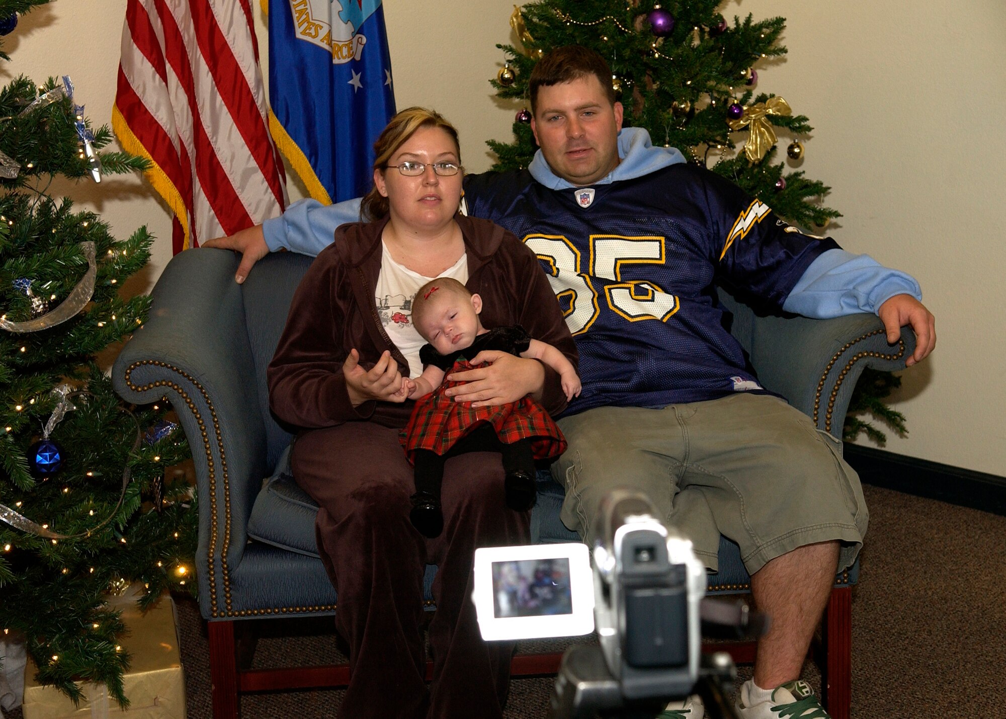 Senior Airman Casey Anderson, 30th Civil Engineer Squadron, along with his wife Dani and daughter Kylie, record a holiday greeting for a deployed friend during the Breakfast with Santa even December 16, 2006, in Vandenberg's Pacific Coast Club.  The greeting will be posted on the Service's website for deployed members to view before Christmas.  (U.S. Air Force photo by Airman 1st Class Stephanie Longoria)           