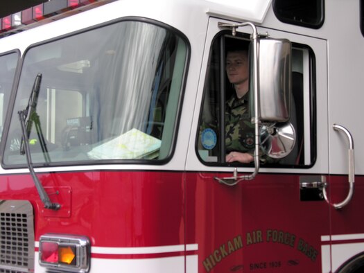 Senior Airman Alan Leckie drives a rescue truck out of the fire station at Hickam Air Force Base, Hawaii. Airman Leckie, assigned to the 15th Civil Engineer Squadron, will work Christmas Day. (U.S. Air Force photo/2nd Lt. Melanie McLean)