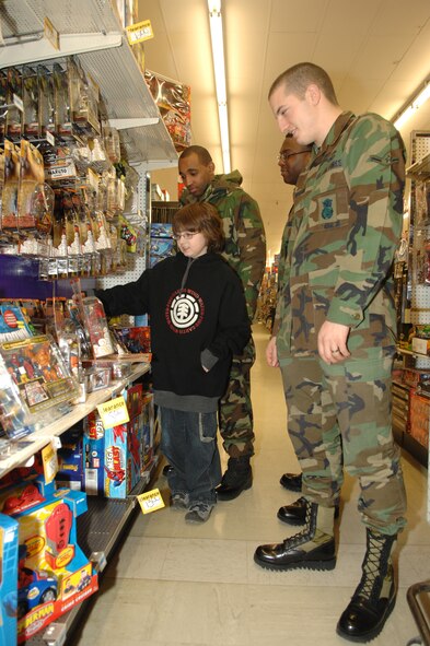 MINOT AIR FORCE BASE, N.D. -- Senior Airman Marcus Carter, Senior Airman Dewaun Bass, and Airman Jonathan Morrison, all with the 5th Security Forces Squadron, look at gifts with Josh Heath at K-Mart in Minot, ND, during the annual "Shop with a Cop" program Dec. 17, 2006. Seventy-seven children received a $100 gift card during this year’s event which helps disadvantaged children during the holiday season to buy presents of their choosing.  Each child is assigned a law enforcement officer to assist with their shopping, but because of the overwhelming outcome, many children were escorted by several adults, such as Heath. (U.S. Air Force photo by Airman 1st Class Christopher Boitz)