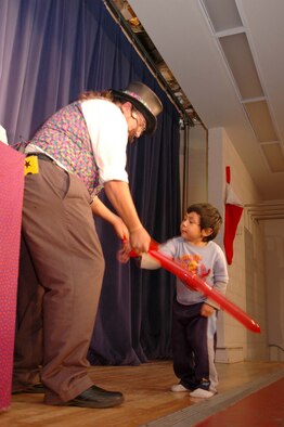 Mr. Jamie O'Hara Magic Guy from Las Cruces makes a ballon animal for Kaiman Ulukita, 4, at the Children's International Festival Saturday. (U.S. photo by Airman Jamal Sutter)