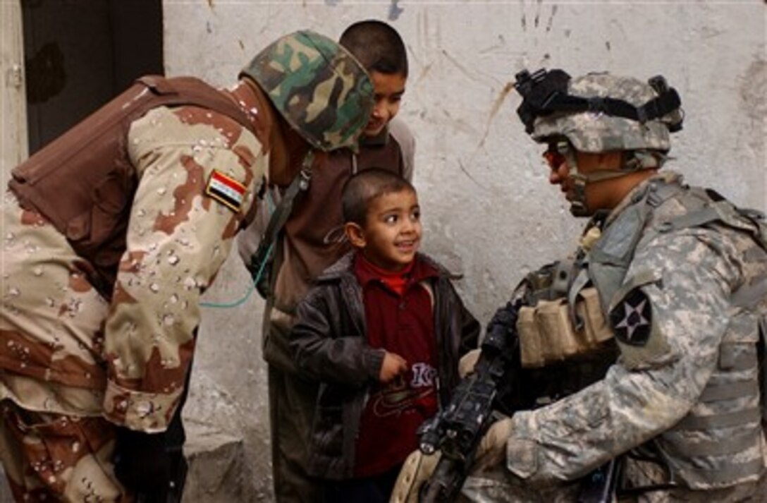 U.S. Army Cpl. Michael Inocencio, right, talks with an Iraqi child, Dec. 17, 2006, during a combined cordon and search operation being conducted with Iraqi army soldiers from the 2nd Battalion, 2nd Brigade, 6th Iraqi Army Division, in Baghdad, Iraq.