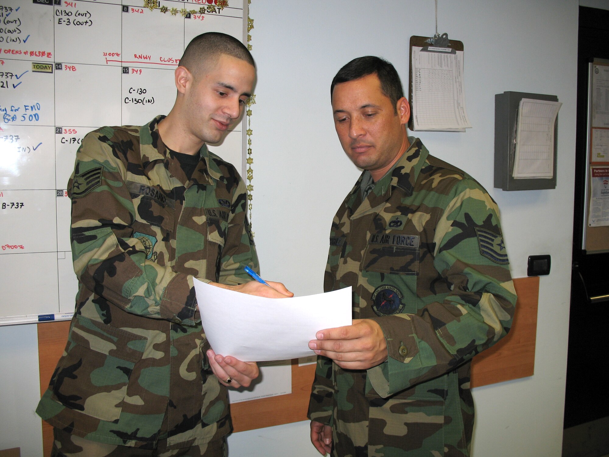 Staff Sgt. Fredric Rosario shows Tech. Sgt. Miguel Rodriguez what time aircraft is scheduled to arrive at Aviano Air Base, Italy. (U.S. Air Force photo/Staff Sgt. Matt Lichtenberg)
