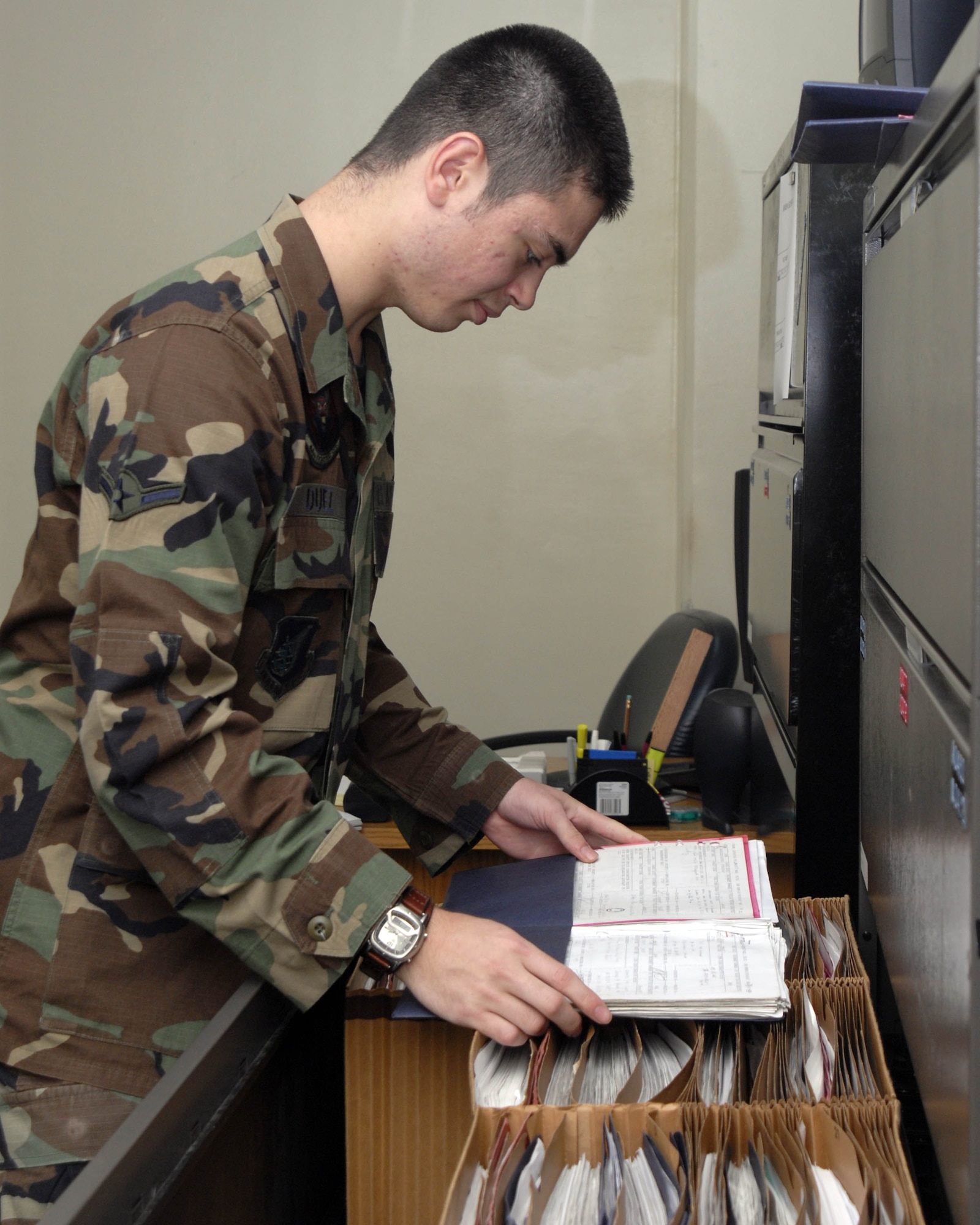Airman VanDexter Duez reviews folders Dec. 13 at Kadena Air Base, Japan.  Airman Duez manages the weekly flying and maintenance schedule for the 44th Aircarft Maintenance Unit. (U.S. Air Force photo/Airman 1st Class Sheila deVera)