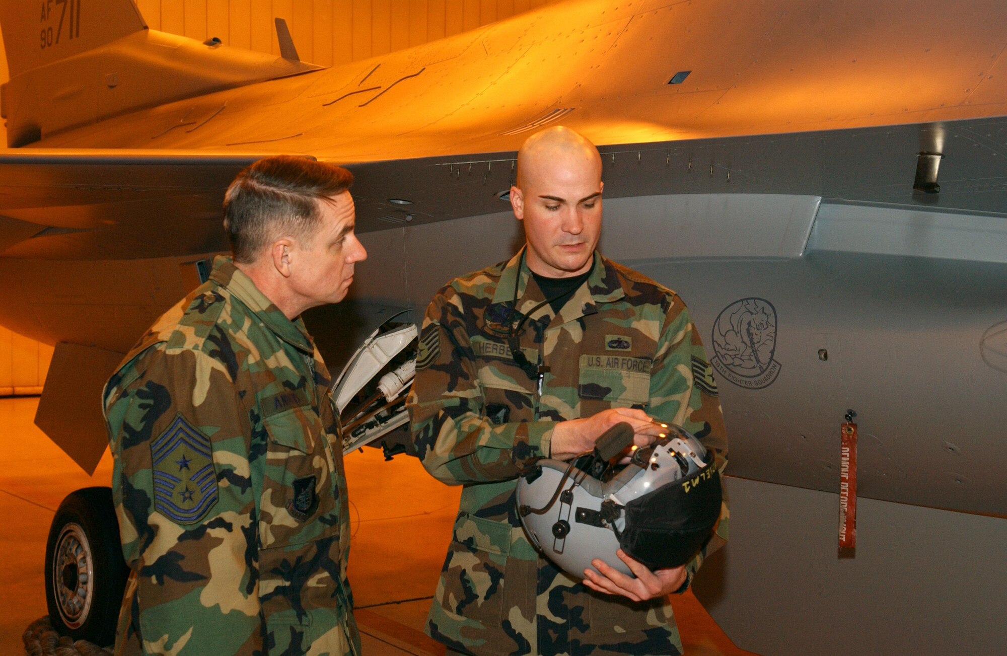 EIELSON AIR FORCE BASE, Alaska -- Technical Sergeant Peter Herbert, 354 AMXS/MXAFS, shows 11th Air Force Command Chief Master Sgt David Andrews a fighter pilots helmet on Dec 19. While visiting Eielson, Chief Andrews stopped by the 18th Aircraft Maintenance Unit for a tour of the building and an exclusive look at a F-16. 
(U.S. Air Force photo by Airman Christopher Griffin.)