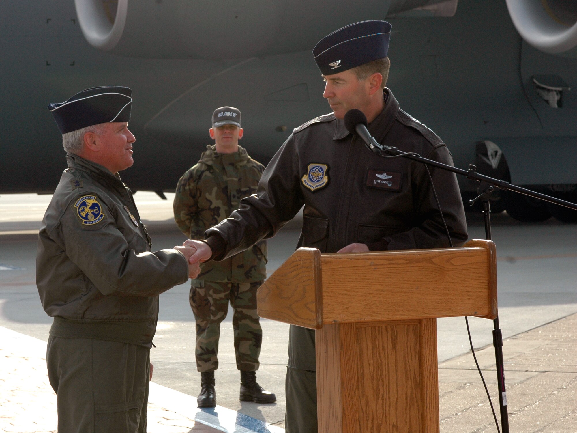 Col. Steve Arquiette, 60th Air Mobility Wing commander, presents Maj. Gen. Allan Poulin, Air Force Reserve Command vice commander, with a Team Travis coin during C-17 arrival ceremony Dec. 20. General Poulin, accompanied by members of the 301st Airlift Squadron, piloted Travis' newest C-17, nicknamed the "Spirit of the Golden Gate," from Long Beach, Calif., to Travis. (U.S. Air Force photo by Staff Sgt. Candy Knight)