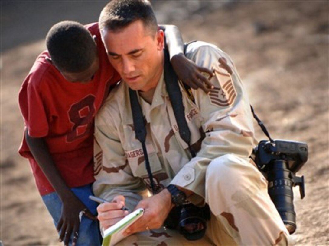 U.S. Air Force Master Sgt. Scott Wagers, a photographer from Combined Joint Task Force - Horn of Africa, writes down the name of an orphan after taking his photograph in Djibouti City, Djibouti, Dec. 12, 2006. Three times a week U.S.servicemembers from Camp Lemonier and CTF-HOA volunteer to the visit orphanage. 