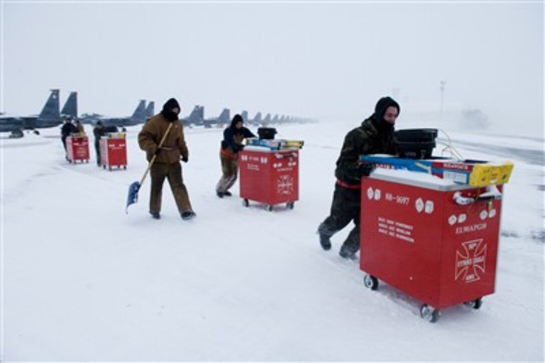 U.S. Air Force Airman 1st Class Jesse Sullivan (right) and fellow airmen with the 90th Air Munitions Unit, 90th Fighter Squadron, push their tool chests out of the snow after working on the flight line at Elmendorf Air Force Base, Alaska, on Dec. 18, 2006.  