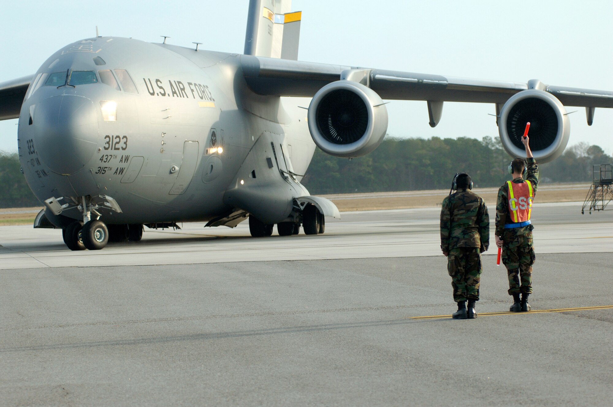 Staff Sgt. Christopher Brown and 2nd Lt. Kevin Ulrich marshal out the first of 20 C-17 Globemaster IIIs Dec. 21 assigned to Charleston Air Force Base, S.C. Aircrews consisting of active-duty Airmen and reservists train simulating the complexity of this type of mission.  The traning mission included airdrops over North Auxiliary Airfield in Orangeburg, S.C., aerial refueling and low-level tactical training. Charleston AFB members launched the largest formation of C-17's to take flight from a single base. Sergeant Brown is from the 315th Aircraft Maintenance Squadron and Lieutenant Ulrich is assigned to the 437th AMXS. (U.S. Air Force photo/Staff Sgt. Marie Cassetty)