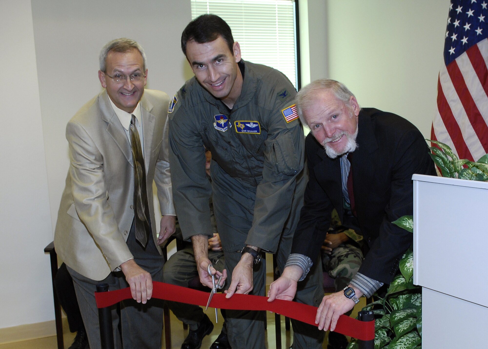 LAUGHLIN AFB, TEXAS -- Colonel Mike Minahan, 47th Flying Training Wing commander, gets ready to cut, as Dr. Mark Underwood, associate dean of South West Texas Junior College, and Dr. Robert Carpenter, education services officer, keep the ribbon tight during the ribbon-cutting ceremony for the education building here.  The education building, which houses three universities, opened in early November.  (U.S. Air Force photo by Jose Mendoza)    