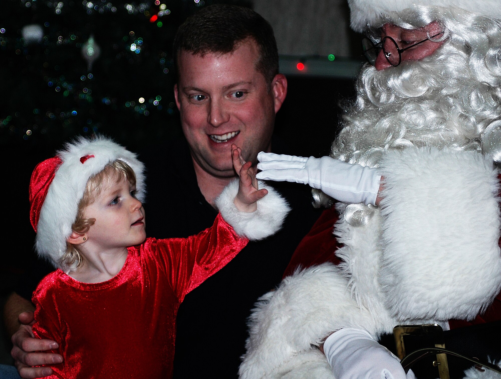 CHICOPEE, Mass. -- Tara Trudeau touches one of Santa Claus' white gloves during the Westover Christmas party held Dec. 9 for Westover Air Reserve Base families. Looking on is dad John Trudeau, an air reserve technician with Westover's 439th Maintenance Squadron. More than 40 children met with Santa during the annual party. The Pioneer Valley USO, located at Westover, manages the party each year. (US Air Force photo by Tech. Sgt. Andrew Biscoe)