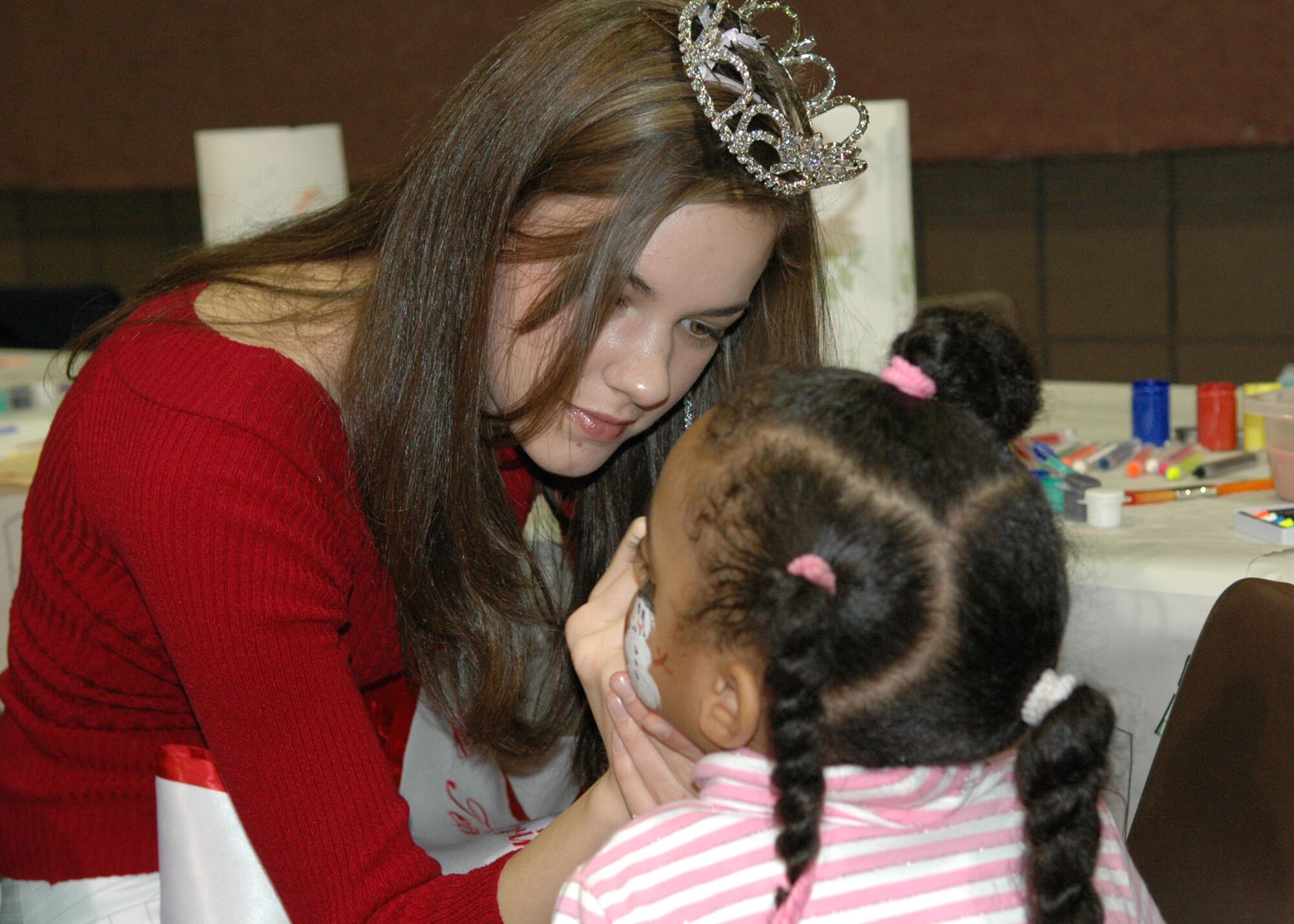 Emiley Reser, Miss Bossier City Teen 2007 and daughter of Master Sgt. John Reser, 917th Wing Ground Safety NCO, paints the face of a child at this year's Santas in Blue program held at the Bossier Civic Center Thursday, Dec. 21. (U.S. Air Force photo/Tech. Sgt. Sherri Savant)