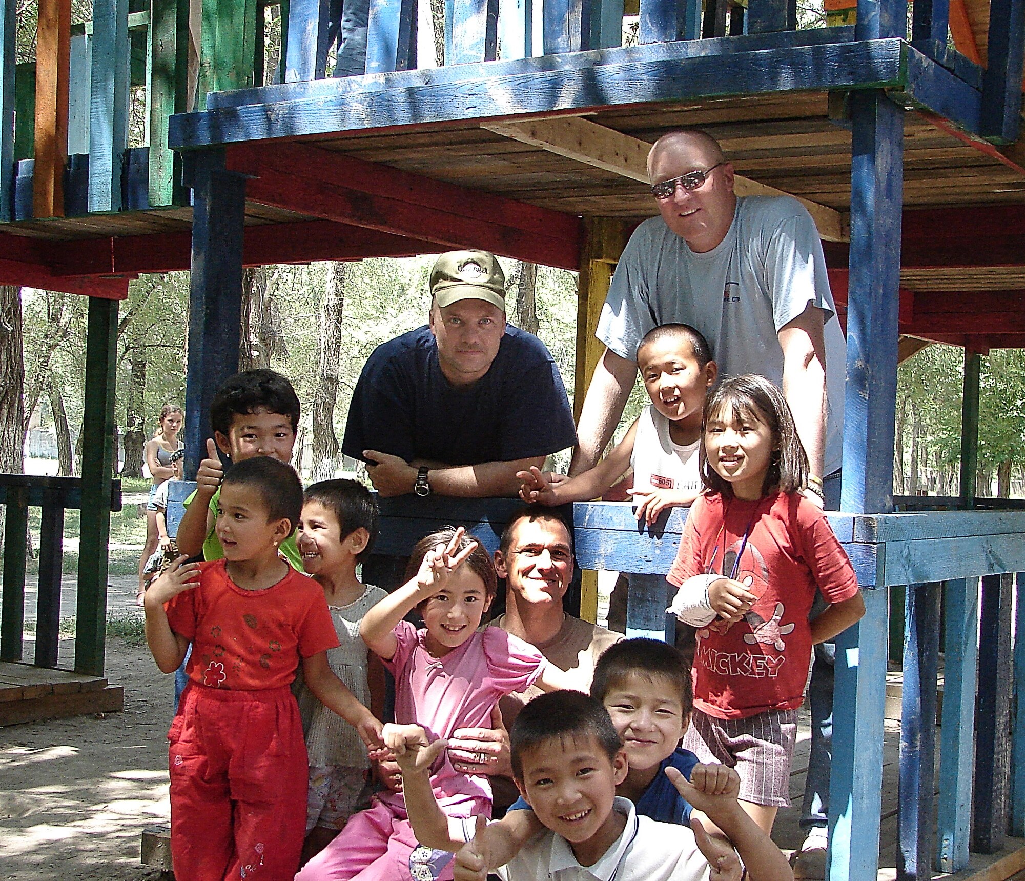 MANAS AIR BASE, Kyrgyzstan -- Air Force reservists from the 442nd Security Forces Squadron, Staff Sgts. Robert Orton and Bryan Byler (back row) and Tech. Sgt. Daniel Heiser (center), play with local kids during one of their visits to remodel the Oktoberski school gym near here. The deployed reservists assisted in several humanitarian service projects. Courtesy photo