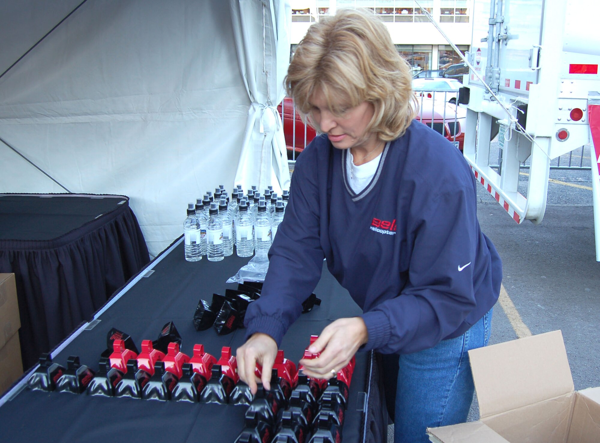 Judy McBride arranges giveaways at the Bell Helicopter booth at a pep rally Dec. 22 at Sundance Square in Fort Worth, Texas. The Bell Helicopter Armed Forces Bowl kicks off at 7 p.m. Dec. 23 at the Amon G. Carter Stadium in Fort Worth. McBride is an employee of Bell Helicopter. (U.S. Air Force photo/Annette Crawford)