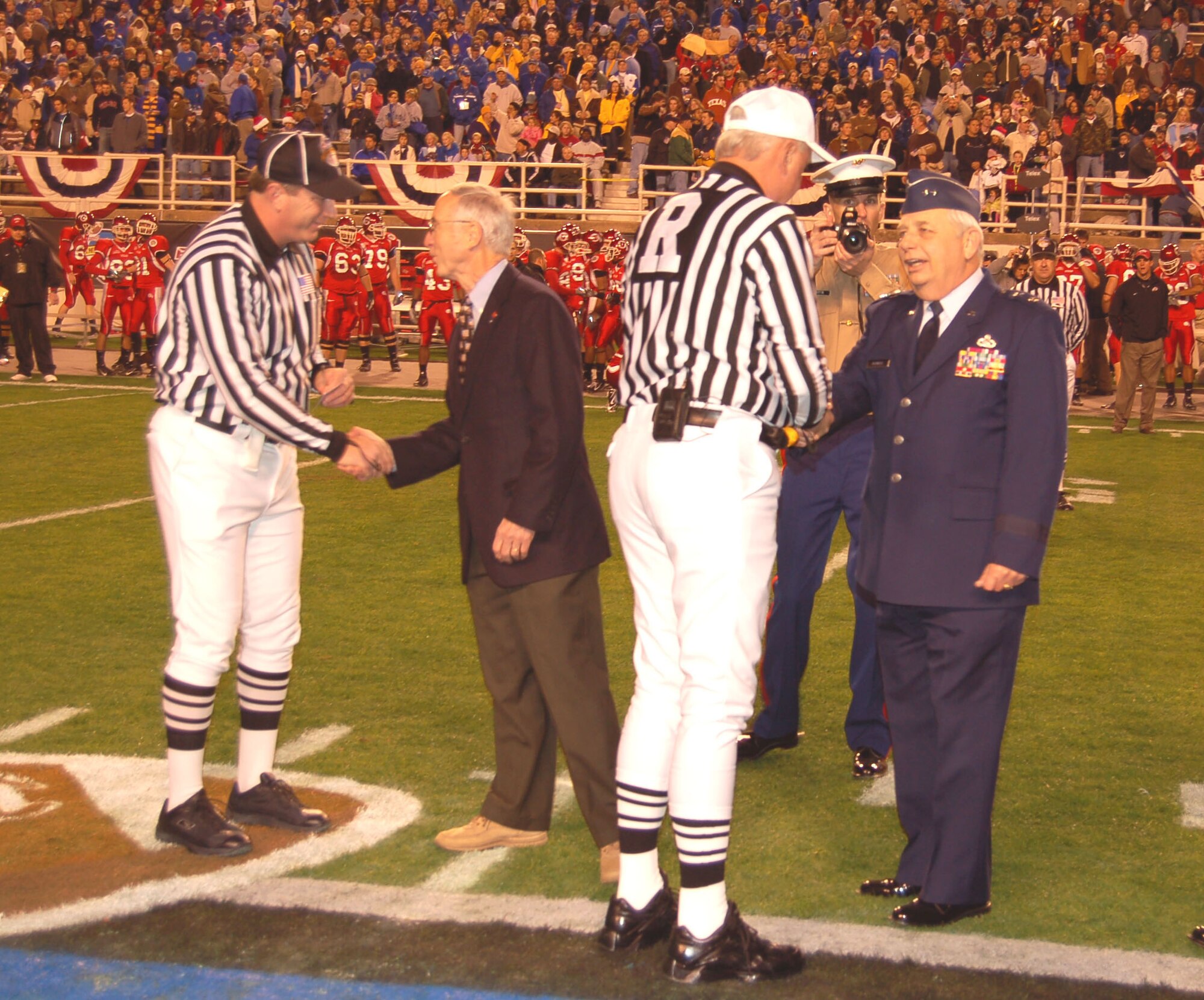 Referees shake hands with Deputy Secretary of Defense Gordon England and Maj. Gen. Allen R. Dehnert, assistant adjutant general and commander, Texas Air National Guard, before the coin toss at the Bell Helicopter Armed Forces Bowl in Fort Worth, Texas, Dec. 23. The University of Utah Utes defeated the Golden Hurricanes of the University of Tulsa, 25-13. (U.S. Air Force photo/Annette Crawford)