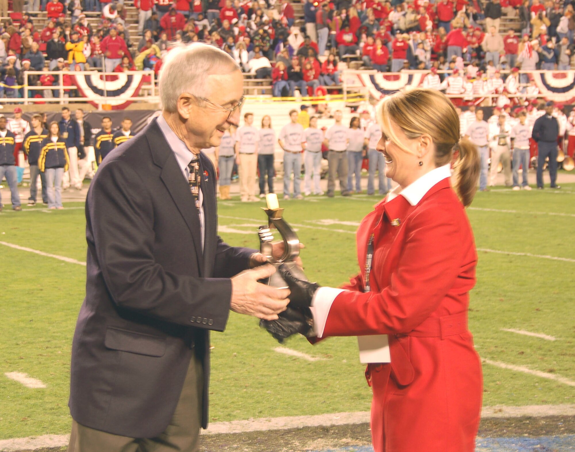Deputy Secretary of Defense Gordon England receives the first Great American Patriot Award from a representative of MA3 LLC at the Bell Helicopter Armed Forces Bowl in Fort Worth, Texas, Dec. 23. The University of Utah Utes defeated the Golden Hurricanes of the University of Tulsa, 25-13. (U.S. Air Force photo/Annette Crawford)

