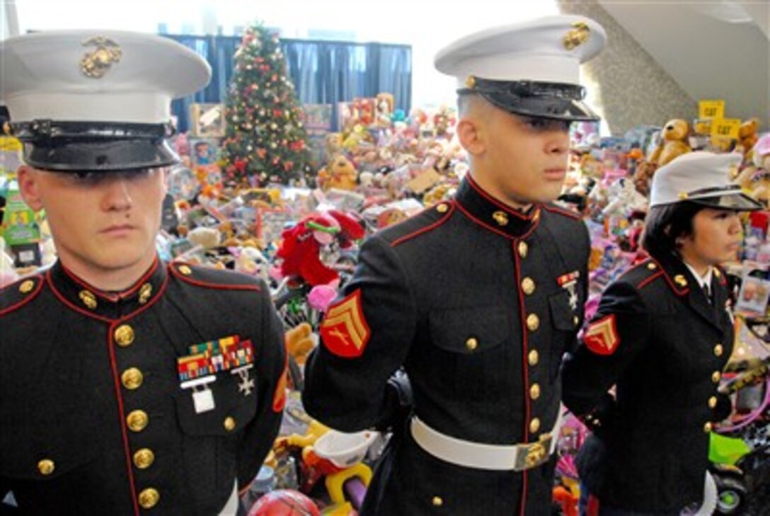 Marines representing Marine Security Guard Battalion, based in Quantico, Va., stand in front of toys collected by State Department members, Dec. 20 at the Harry S. Truman Building, in Washington. From left are Sgt. Kevin D. Prindable of Granite City, Ill.; Cpl. Bryson M. Jones of Washington Court House, Ohio, and Cpl. Ella J. Asuncion of St. Paul, Minn. 
